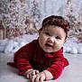 baby, child, closeup, cute, decorations, face, festive, hands, happy, headband, holiday, indoor, infant, lying_down, portrait, red_dress, smiling, soft_lighting, toddler, winter_theme