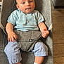 baby, infant, child, baby_seat, blue_shirt, striped_pants, socks, wooden_floor, gray_fabric, indoor, cute, portrait, young_child, seated, comfortable, curious, person, casual_clothing, home_interior, relaxed