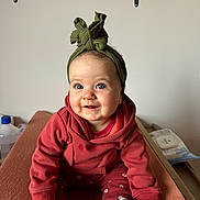 Margot participe au concours pour gagner de l'argent avec cette photo : baby, bodypart, clothing, couch, face, finger, footwear, furniture, hand, happy, head, knitwear, pants, person, photography, portrait, shoe, sitting, smile, wood