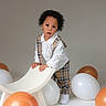 Owen joined the competition — help win amazing prizes! toddler, child, balloons, white_shirt, plaid_clothing, suspenders, white_shoes, chair, studio, gray_background, curly_hair, standing, playful, indoor, fashion, cute, portrait, young_child, expression, floor