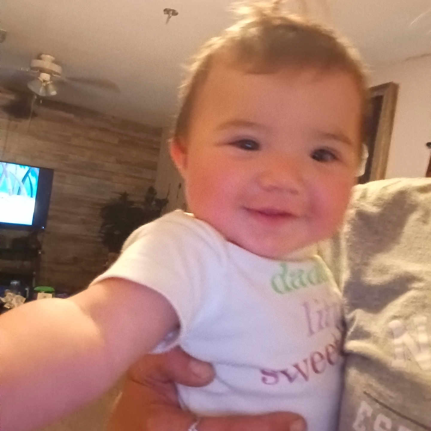 Macee joined the competition — help win amazing prizes! adult_hand, baby, ceiling_fan, child, closeup, cozy, furniture, hair, hand, happy, home, indoor, living_room, person, pony_tail, portrait, ring, smiling, television, tshirt