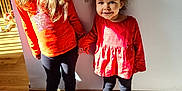 Laïna a rejoint le concours — aidez-le/la à gagner de superbes lots ! barefoot, child, children, curly_hair, floor, girl, happy, holding_hands, home, indoor, leggings, long_hair, portrait, red_clothing, shadow, smiling, sock, standing, sunlight, wall
