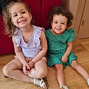 Laïna participe au concours pour gagner de l'argent avec cette photo : casual_clothing, child, children, curly_hair, cute, floor, green_dress, happy, home, indoors, person, portrait, purple_top, red_couch, sitting, smiling, two_people, white_sandals, wooden_floor, young