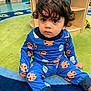 toddler, child, pajamas, blue, milk, cookie, sitting, rug, classroom, floor, curly_hair, indoor, playroom, furniture, expression, person, cute, young, clothing, colorful