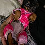 dog, puppy, pink_pajamas, pet, sleepy, cute, small_dog, cozy, blanket, resting, indoor, animal, fur, paws, human_hand, relaxed, mammal, companion, adorable, snuggle