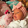 Sophia is registered to the contest to win money with this photo: newborn, baby, infant, pink_bow, mittens, plush_toy, soft_toy, floral_bedding, sleepwear, cozy, cute, face, portrait, indoors, child, headband, patterned_clothing, closeup, resting, snuggling