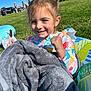 child, girl, smiling, towel, popsicle, grass, sunny_day, outdoor, inflatable_float, colorful_clothing, people, park, summer, happy, nature, playful, fun, relaxing, daylight, casual