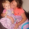 Emery joined the competition — help win amazing prizes! child, toddler, blanket, cup_lid, couch, hug, kiss, indoor, person, clothing, pink, purple, blond_hair, brown_hair, comfort, family, affection, seated, casual, cute