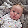 baby, child, infant, curly_hair, blue_eyes, onesie, animal_print, blanket, soft_texture, cozy, cute, portrait, indoors, face, expression, child_clothing, resting, comfort, young_child, closeup