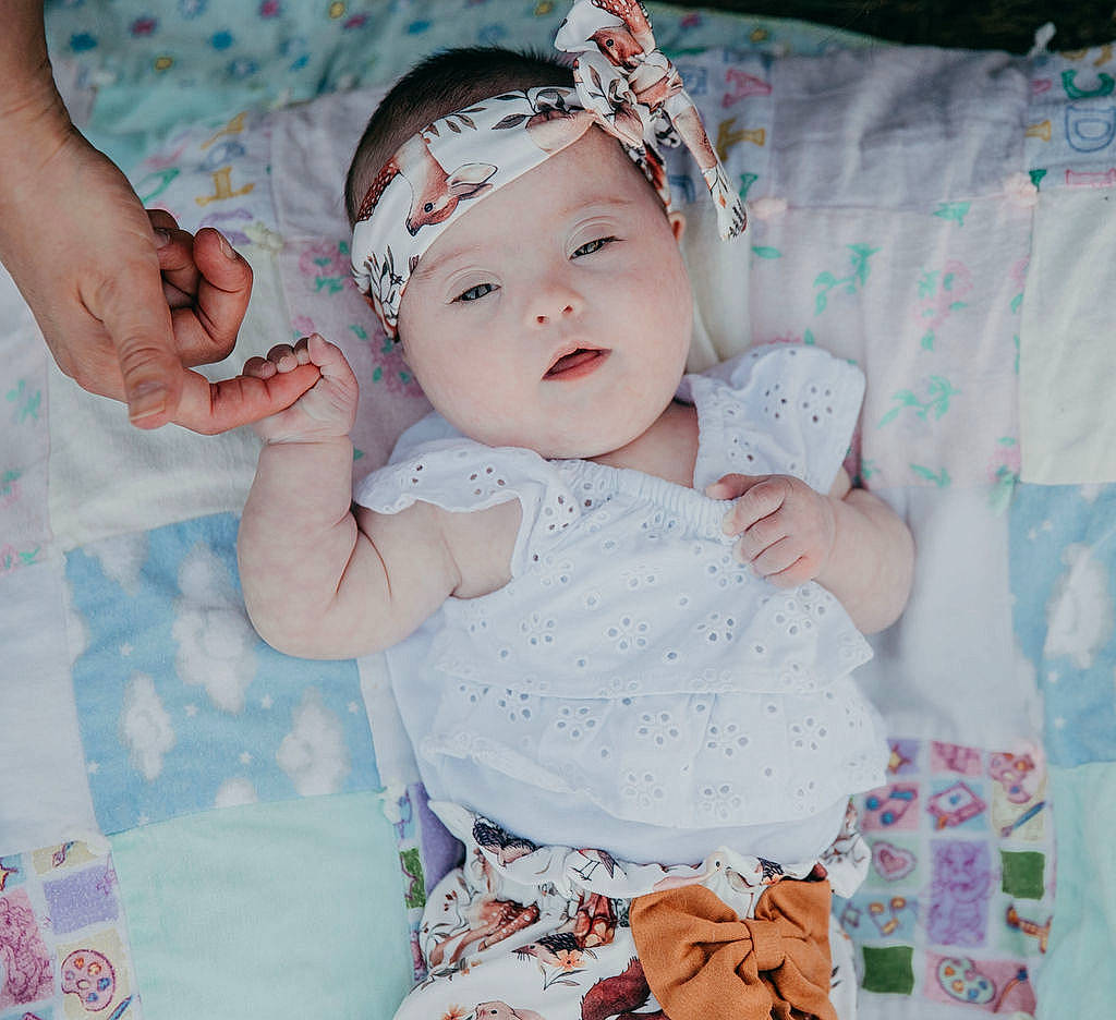 Brynlee joined the competition — help win amazing prizes! baby, baby_toddler_clothing, cap, child, embellishment, fashion_accessory, finger, gesture, hand, happy, headband, headgear, headpiece, headwear, pattern, person, pink, skin, sleeve, textile