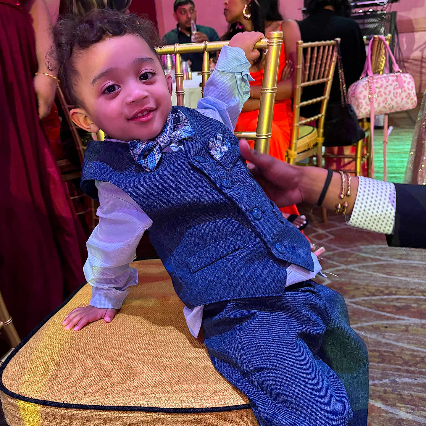 Lazhi Solomon is registered to the contest to win money with this photo: toddler, child, boy, suit, bow_tie, chair, party, indoor, smile, curly_hair, person, fashion, event, people, furniture, hand, background, dress, lighting, candid