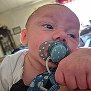 Miles Lee is registered to the contest to win money with this photo: baby, background, blue, blur, child, closeup, clothing, expression, face, grip, hand, head, indoor, infant, pacifier, pattern, person, room, skin, white