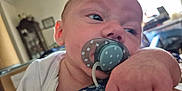 Miles Lee is registered to the contest to win money with this photo: baby, background, blue, blur, child, closeup, clothing, expression, face, grip, hand, head, indoor, infant, pacifier, pattern, person, room, skin, white
