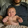 Miles Lee is registered to the contest to win money with this photo: man, baby, child, person, indoor, couch, towel, smile, holding, relaxed, beard, shirt, blanket, happy, skin, face, hand, seated, portrait, family