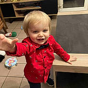 Elyo a rejoint le concours — aidez-le/la à gagner de superbes lots ! toddler, child, red_shirt, indoor, toy, floor, table, window, smiling, person, blond_hair, room, furniture, playful, young_child, casual_clothing, home, floor_tile, reaching_hand, curious