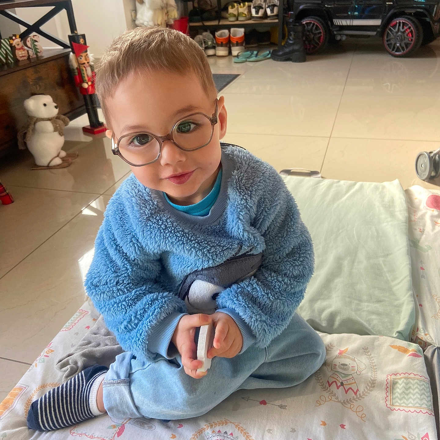 Elvys participe au concours pour gagner de l'argent avec cette photo : blue_sweater, carpet, child, cozy, cute, face, floor, furniture, glasses, home, indoor, person, play, puzzle, sitting, smile, socks, toddler, toy, toy_car