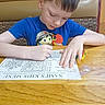 Hunter joined the competition — help win amazing prizes! child, boy, young, face, portrait, sitting, table, wooden_table, coloring, activity_sheet, crayons, drawing, cartoon, blue_shirt, indoors, restaurant, booth, focused, hands, paper