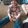 child, smiling, bird, animal, indoor, carpet, living_room, plaid_shirt, winter_hat, blue_jeans, sitting, cross_legged, hands, portrait, family, furniture, couch, soft_focus, casual, pet