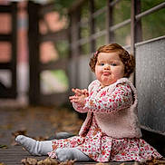 Amélia a rejoint le concours — aidez-le/la à gagner de superbes lots ! autumn, baby, child, curly_hair, cute, daylight, fallen_leaves, floral_dress, funny_face, nature, outdoor, pink_vest, playful_expression, portrait, railings, sitting, toddler, tongue_out, white_tights, wooden_path