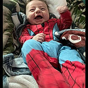 Micah joined the competition — help win amazing prizes! baby, child, smiling, happy, spiderman_outfit, blanket, cozy, indoor, cute, infant, portrait, clothing, laughing, young_child, person, head, face, warm, soft, relaxed