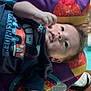 Micah is registered to the contest to win money with this photo: baby, blanket, child, clothing, colorful, curious, cute, face, graphic, hand, indoor, infant, lying, portrait, rainbow, relaxed, shirt, skin, soft_light, young