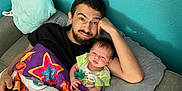 Micah joined the competition — help win amazing prizes! baby, beard, blanket, casual, colorful, comfort, couch, family, father_and_child, green_shirt, home, indoor, man, pillow, portrait, relaxing, resting, smile, star_pattern, toddler