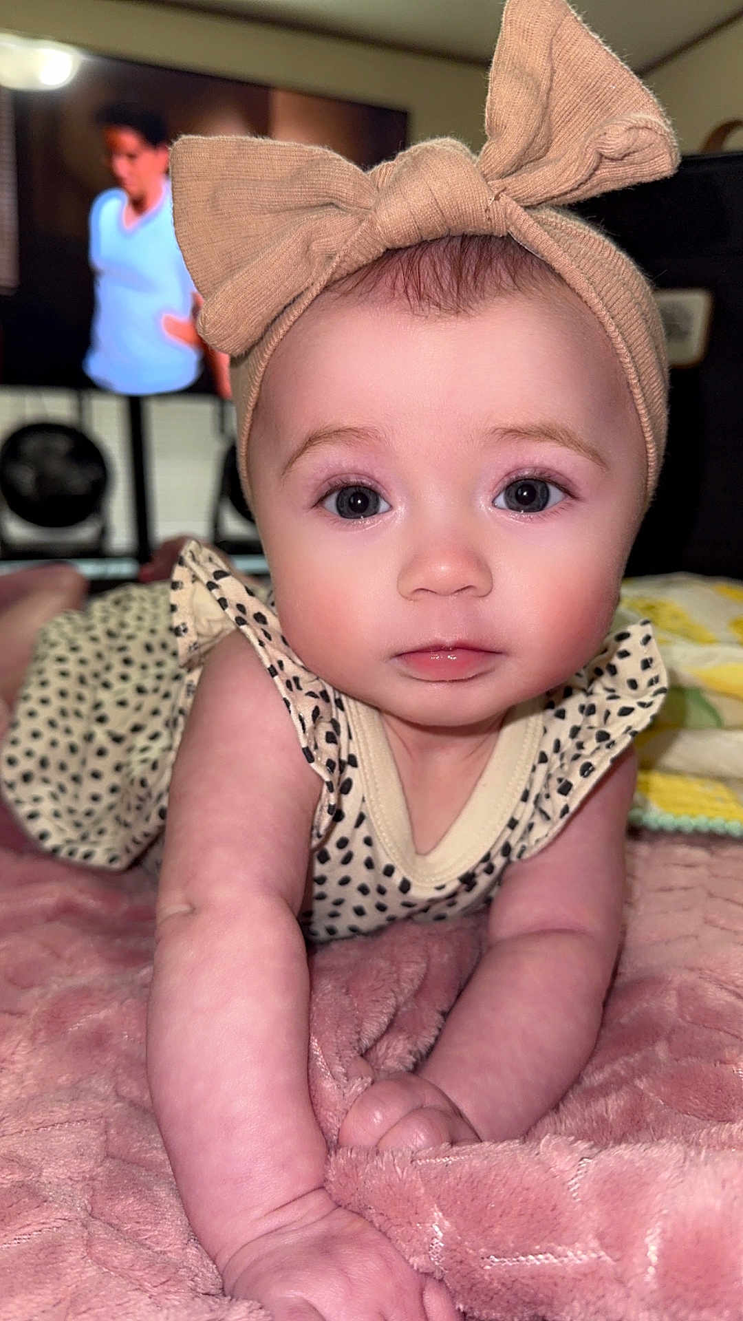 Wrenleigh is registered to the contest to win money with this photo: baby, child, headband, bow, blanket, crawling, indoor, person, face, skin, eyes, expression, clothing, pink, soft, home, furniture, television, blurred_background, cute