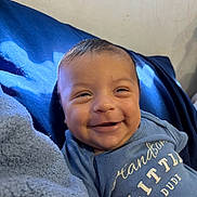 Josiah is registered to the contest to win money with this photo: baby, smiling, blue_clothing, blanket, face, infant, happy, child, portrait, cute, lying_down, toddler, indoors, soft_light, skin, head, eyes, mouth, expression, human