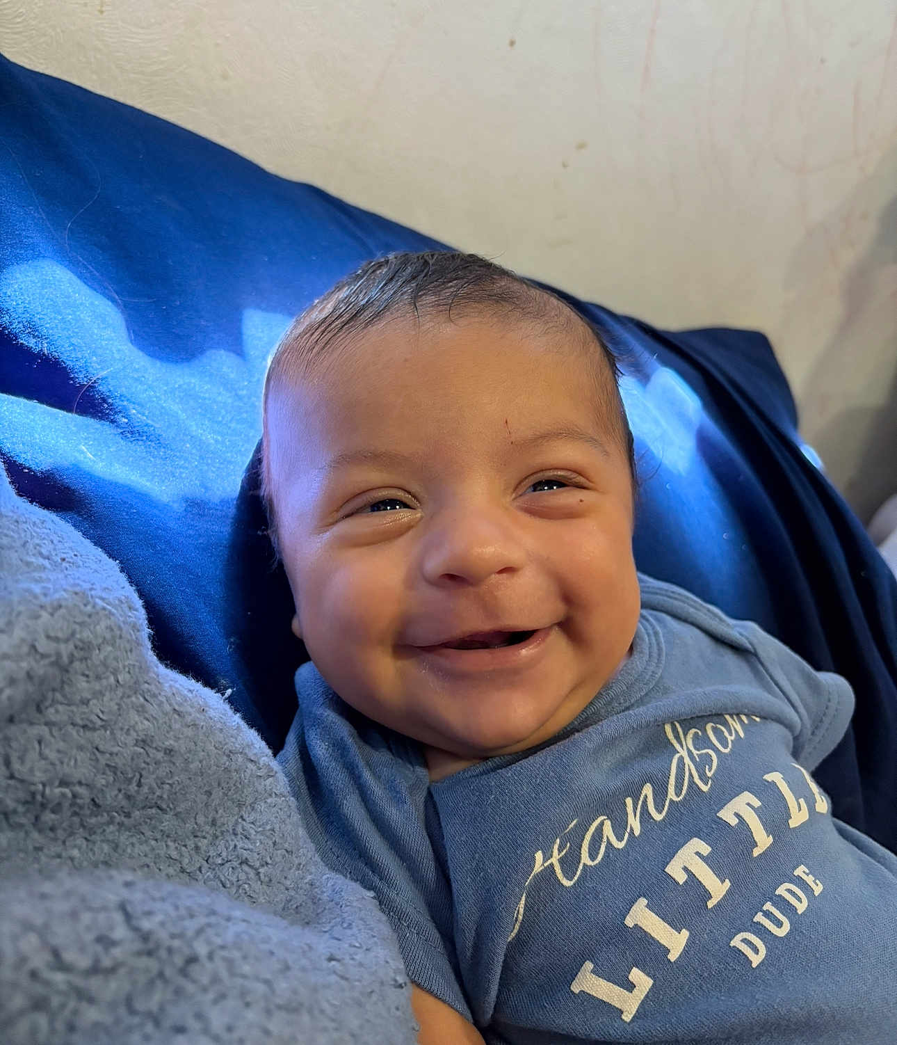 Josiah is registered to the contest to win money with this photo: baby, smiling, blue_clothing, blanket, face, infant, happy, child, portrait, cute, lying_down, toddler, indoors, soft_light, skin, head, eyes, mouth, expression, human