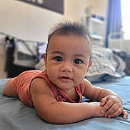 Erwan participe au concours pour gagner de l'argent avec cette photo : baby, bed, bedroom, blue_bedspread, blurred_background, child, curious, eyes, face, hair, hands, indoors, infant, orange_clothing, portrait, skin, soft_light, striped_outfit, sunlight, window