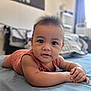baby, bed, bedroom, blue_bedspread, blurred_background, child, curious, eyes, face, hair, hands, indoors, infant, orange_clothing, portrait, skin, soft_light, striped_outfit, sunlight, window