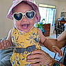 Durrann joined the competition — help win amazing prizes! adult_hand, baby, child, cute, fashion, furniture, hand, happy, hat, indoor, joyful, living_room, person, plant, portrait, smile, sunglasses, watch, window, yellow_dress