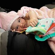 Durrann is registered to the contest to win money with this photo: baby, blanket, calm, child, colorful, cozy, cute, expression, fabric, face, hand, hat, indoor, infant, lying_down, pink, portrait, resting, soft, toy