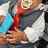 Davontae is registered to the contest to win money with this photo: baby, blue_toy, child, clothing, couch, cute, expression, formal_clothing, gray_suit, green_wall, hand, indoor, infant, pacifier, people, person, portrait, red_tie, sitting, toy