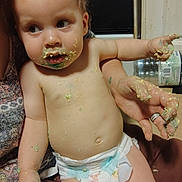 Dylan is registered to the contest to win money with this photo: baby, toddler, child, diaper, messy, cake, food, crumbs, face, hand, arm, skin, person, indoor, kitchen, adult_hand, curious, smudged, closeup, sitting