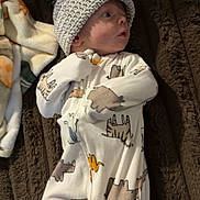 Ryker joined the competition — help win amazing prizes! baby, infant, knitted_hat, onesie, animal_print, blanket, fleece_blanket, brown_blanket, lying_down, cute, soft_texture, pom_pom, sleepwear, child, newborn, portrait, indoor, warm, cozy, curious