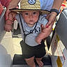 Buck is registered to the contest to win money with this photo: baby, child, hat, straw_hat, tshirt, shorts, barefoot, adult_hand, boat, seat, interior, person, helping_hand, summer, outdoor, cute, determined, walking, support, casual_clothing