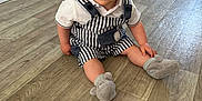 Maylonn participe au concours pour gagner de l'argent avec cette photo : baby, child, cute, eyes, face, floor, footwear, hand, happy, home, indoor, infant, overalls, person, plush_slippers, sitting, smiling, striped_clothing, white_shirt, wooden_floor
