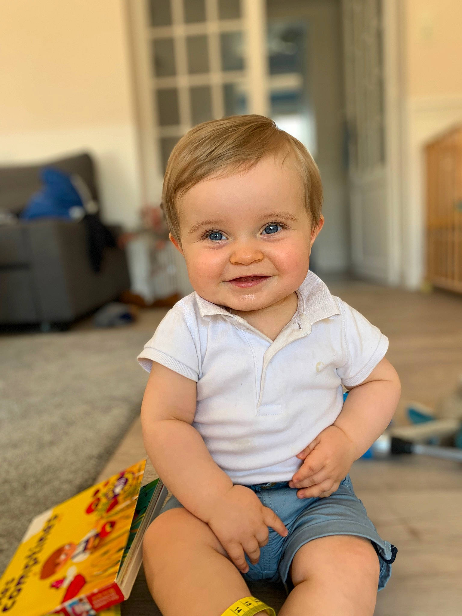 Arsène participe au concours pour gagner de l'argent avec cette photo : baby, baby_toddler_clothing, cheek, child, chin, face, finger, floor, flooring, fun, happy, iris, joy, person, shorts, skin, sleeve, smile, standing, t_shirt