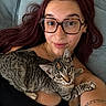 woman, cat, glasses, purple_hair, tabby_cat, couch, tattoo, selfie, indoor, relaxed, pet, laying_down, black_top, closeup, face, feline, human, portrait, casual, cozy