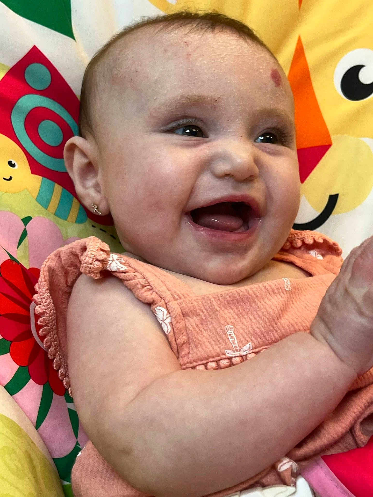Blakelynn joined the competition — help win amazing prizes! baby, child, smiling, laughing, peach_clothing, earrings, face, arm, colorful_background, flower_pattern, infant, happy, cute, playful, portrait, closeup, skin, young_child, indoors, cheerful
