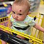 Blakelynn joined the competition — help win amazing prizes! baby, shopping_cart, child, infant, dress, floral_pattern, face, red_mark, supermarket, yellow, seatbelt, person, cute, shopping, aisle, blurred_background, indoor, expression, young_child, seated