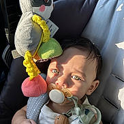 Noah is registered to the contest to win money with this photo: baby, pacifier, car_seat, toy, stuffed_animal, child, infant, sunlight, shadow, seatbelt, cute, toddler, closeup, face, hand, clothing, indoor, comfort, relaxation, childcare