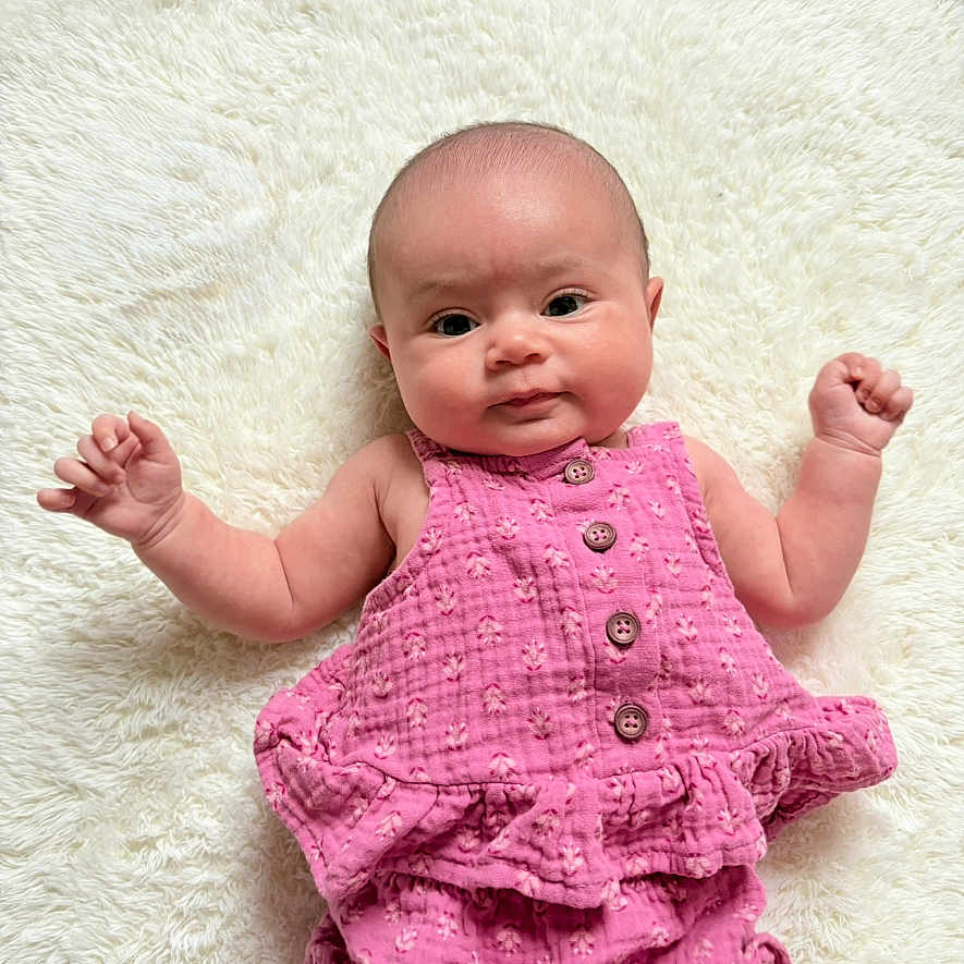 Delilah joined the competition — help win amazing prizes! baby, bodypart, bonnet, clothing, dress, face, finger, hand, happy, hat, head, newborn, pants, person, photography, portrait, quilt, shorts, sitting, smile