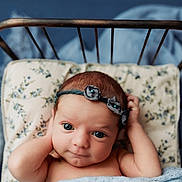 Ellis is registered to the contest to win money with this photo: baby, infant, headband, flower, pillow, bed, blanket, blue, cute, portrait, skin, face, eyes, newborn, resting, indoors, sleepwear, child, young, cozy