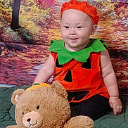 Jacob Ap is registered to the contest to win money with this photo: autumn, baby, background, blanket, child, cute, festive, green, halloween, hat, holiday, indoor, orange, person, plush_toy, portrait, pumpkin_costume, sitting, smiling, teddy_bear