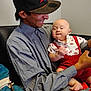 Jacob Ap is registered to the contest to win money with this photo: man, baby, child, cap, shirt, red_clothing, couch, indoor, smile, holding, happy, person, toddler, seated, casual, portrait, interaction, family, skin, arm