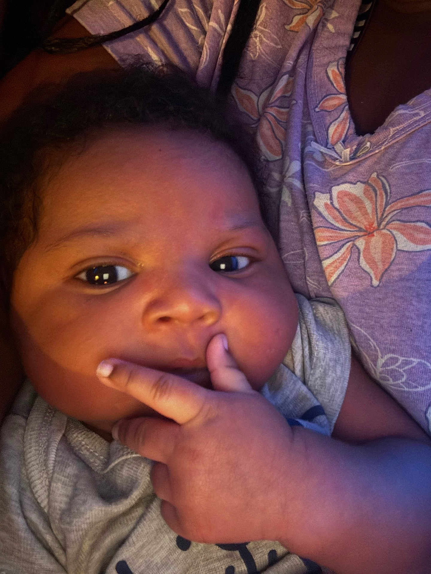 Cason is registered to the contest to win money with this photo: baby, infant, close_up, face, hand, fingers, curly_hair, chubby_cheeks, soft_lighting, gray_clothing, floral_pattern, person, skin, cute, portrait, resting, indoor, warm_tones, expression, child