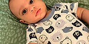 Mateo is registered to the contest to win money with this photo: baby, infant, onesie, bear_pattern, green_blanket, lying_down, curious_expression, child, cute, soft_lighting, indoors, portrait, small_hand, closeup, young_child, face, head, skin, sleepwear, patterned_clothing