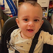 Mateo is registered to the contest to win money with this photo: animal_print, arm, baby, baby_face, child, clothing, cute, eyes, face, furniture, happy, high_chair, indoor, infant, onesie, person, portrait, seatbelt, smiling, young_child